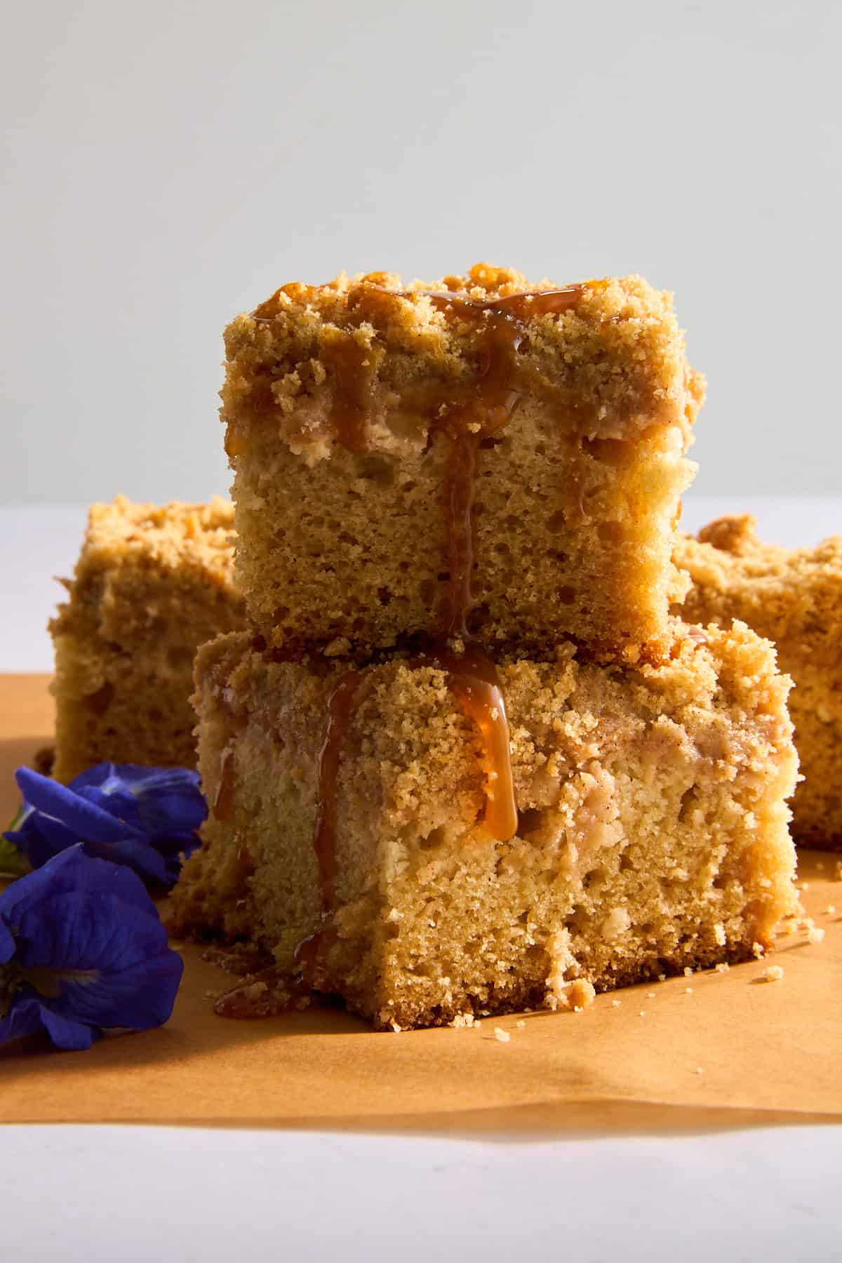 Two pieces of apple crumb cake on top of each other topped with caramel sauce. 