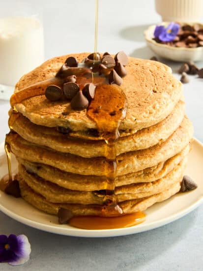 A stack of protein chocolate chip pancakes topped with chocolate chips and syrup.