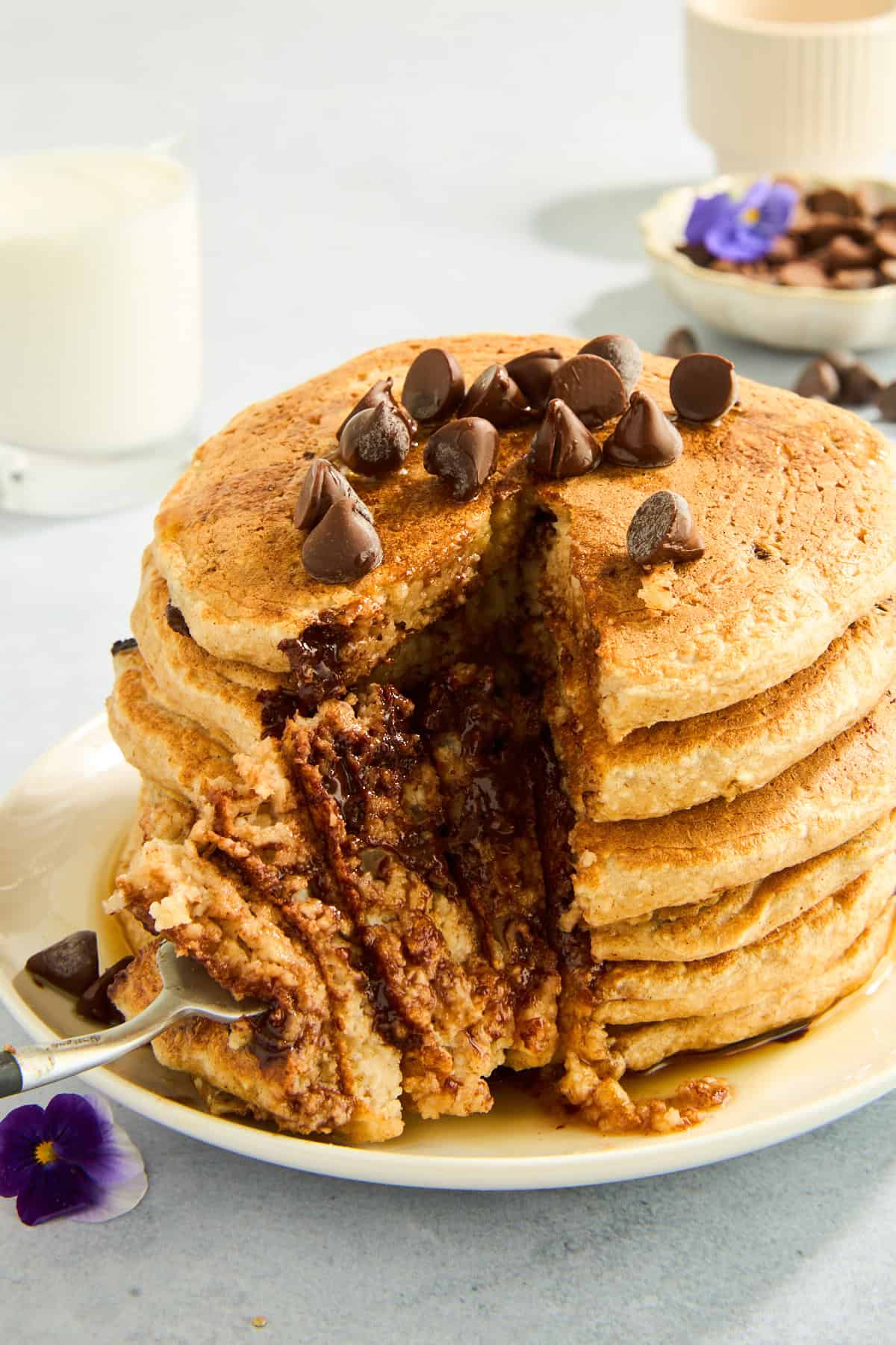 A stack of protein chocolate chip pancakes with a fork holding a bite. 