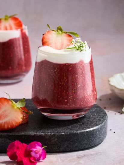 A jar of strawberry chia pudding topped with yogurt and a strawberry.