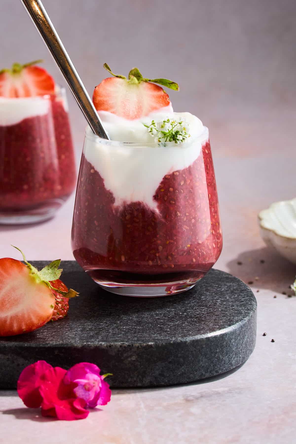 A jar of strawberry chia pudding topped with yogurt and a strawberry.