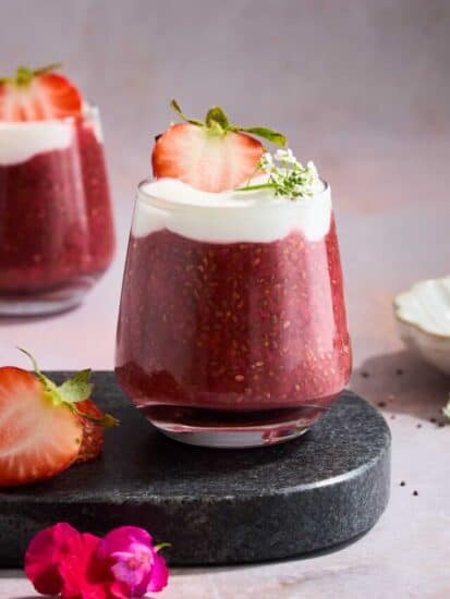 A jar of strawberry chia pudding topped with yogurt and a strawberry.