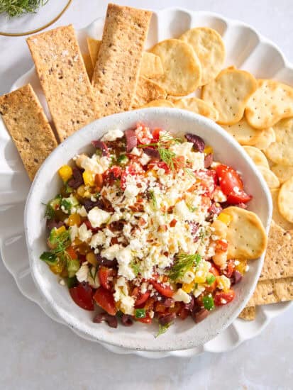 Overhead image of a bowl of Mediterranean feta dip on a plate with crackers.