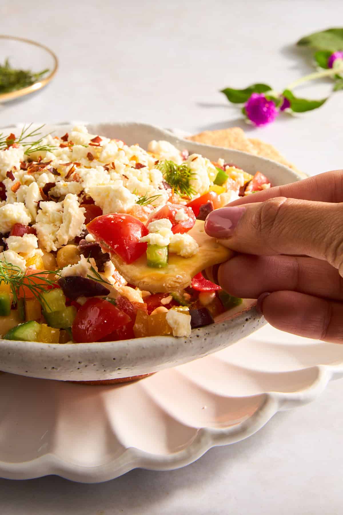 A pita chip being dipped into a bowl of Mediterranean dip.