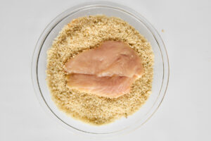 Raw chicken being breaded.