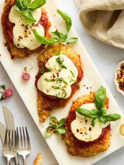 Three pieces of baked chicken parmesan on a platter.