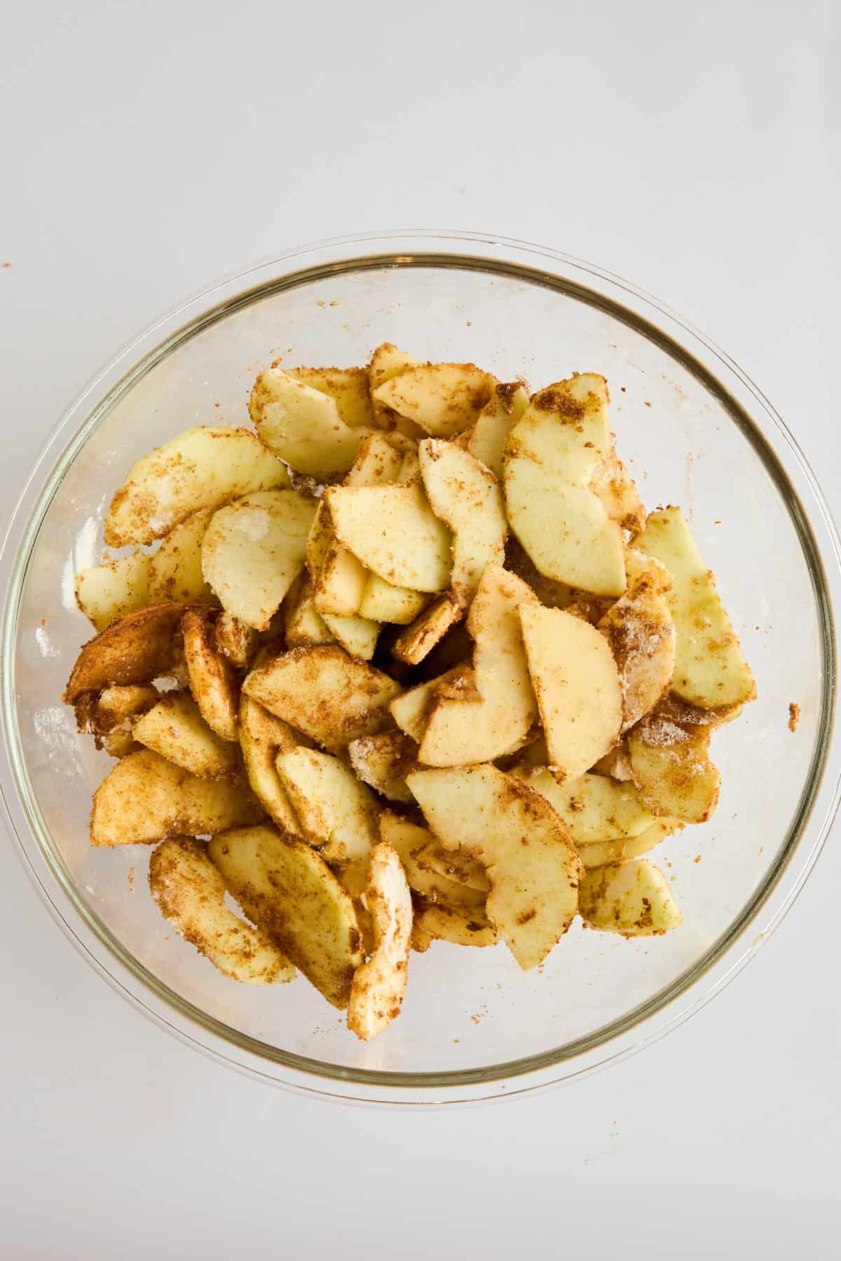 Seasoned apples in a mixing bowl. 