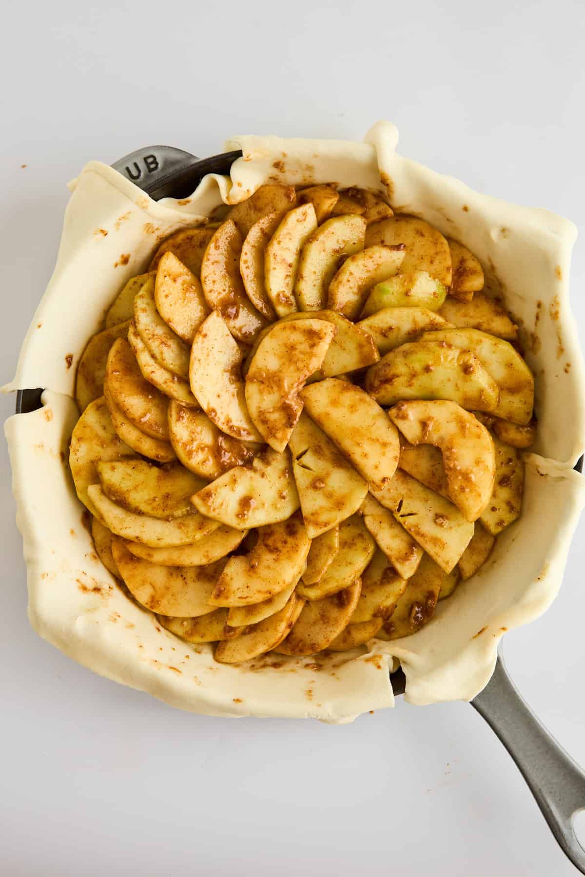 Apple pie filling layered over puff pastry in a skillet. 