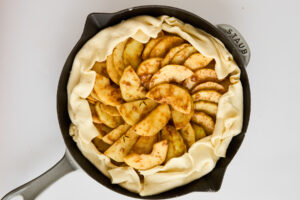 Puff pastry folded over apple filling in a skillet.