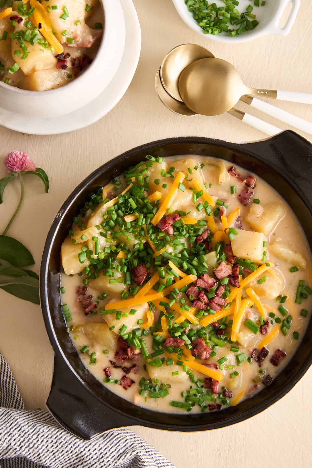 A bowl of cheesy potato soup topped with chives, bacon, and shredded cheese. 