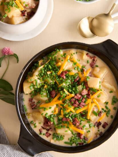 Overhead image of a bowl of cheesy potato soup topped with chives, cheese, and bacon.