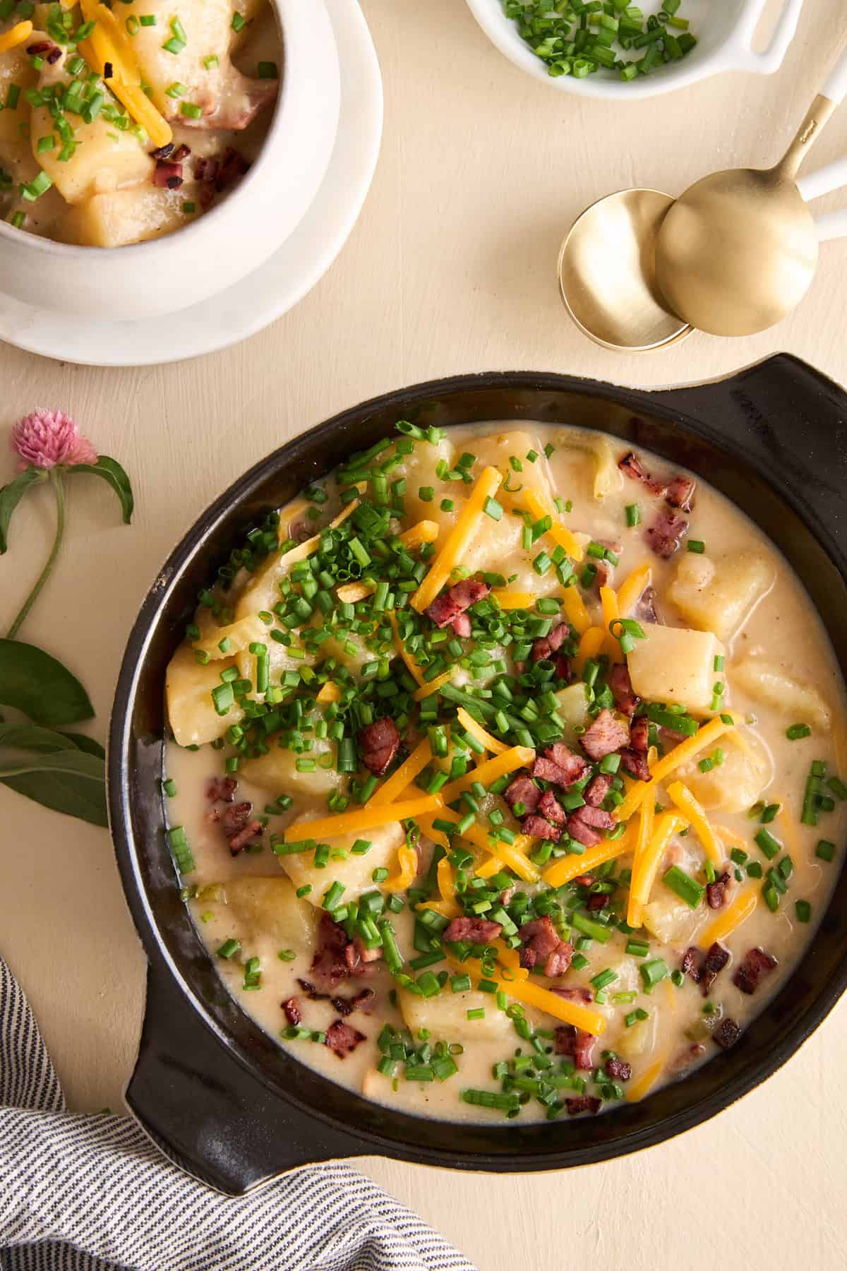 Overhead image of a bowl of cheesy potato soup topped with chives, cheese, and bacon.