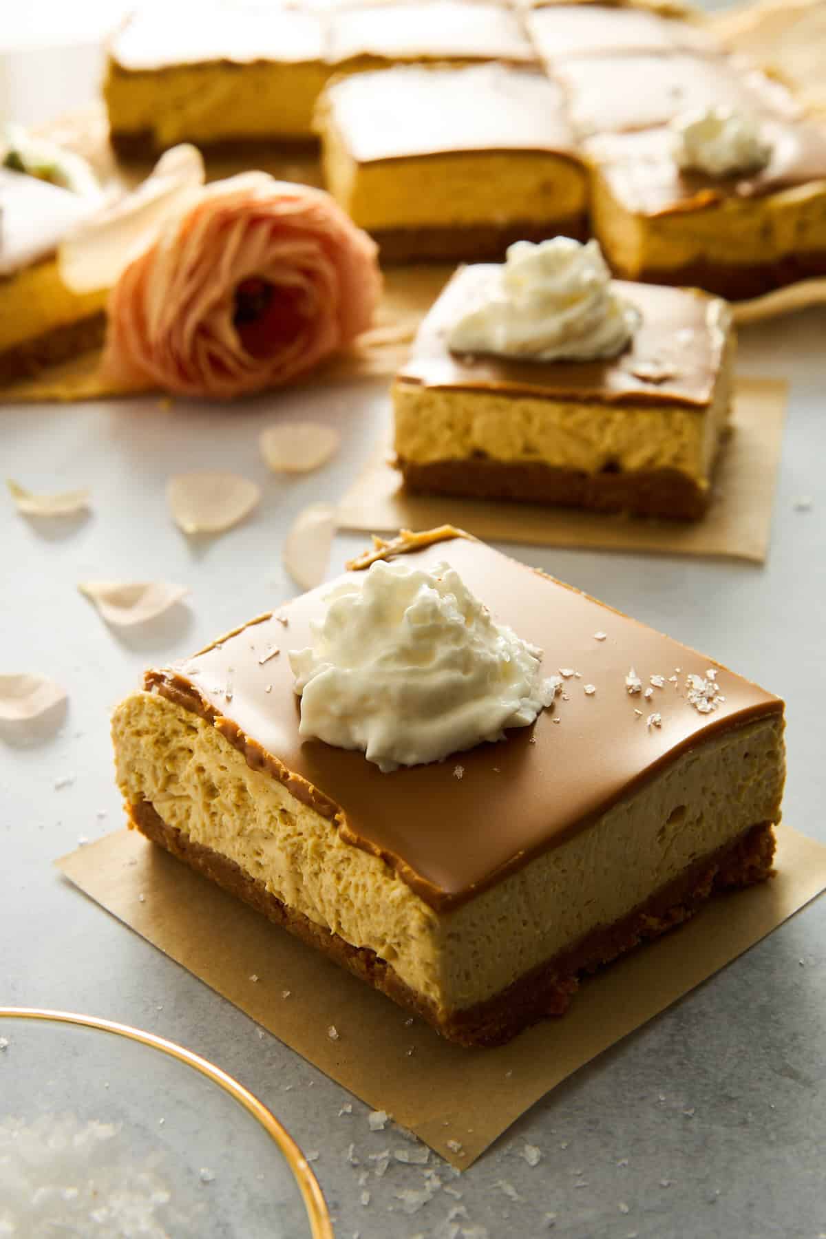 No-bake pumpkin cheesecake bars topped with whipped cream and salt. 