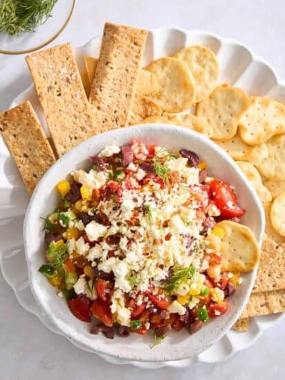 Overhead image of a bowl of Mediterranean feta dip on a plate with crackers.