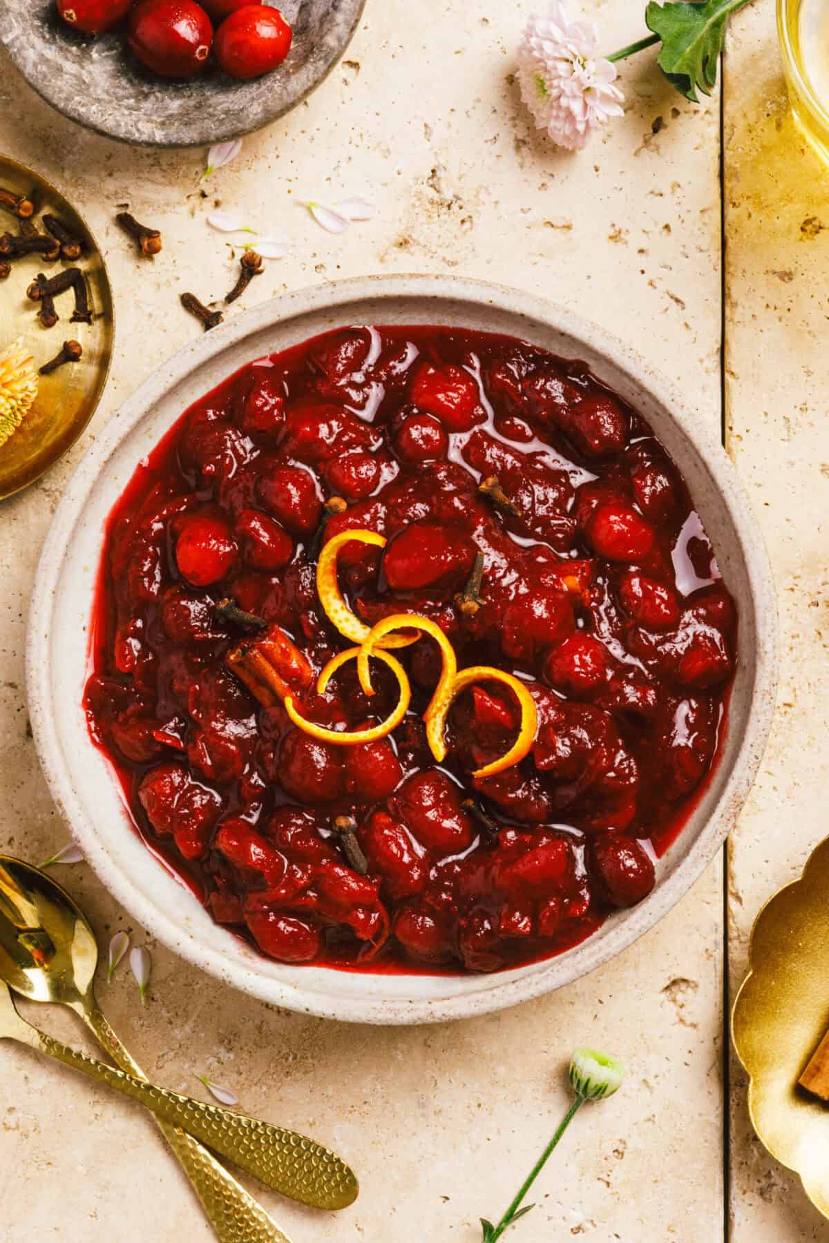 A bowl of homemade cranberry sauce topped with citrus peels. 