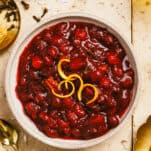 A bowl of homemade cranberry sauce topped with citrus peels.