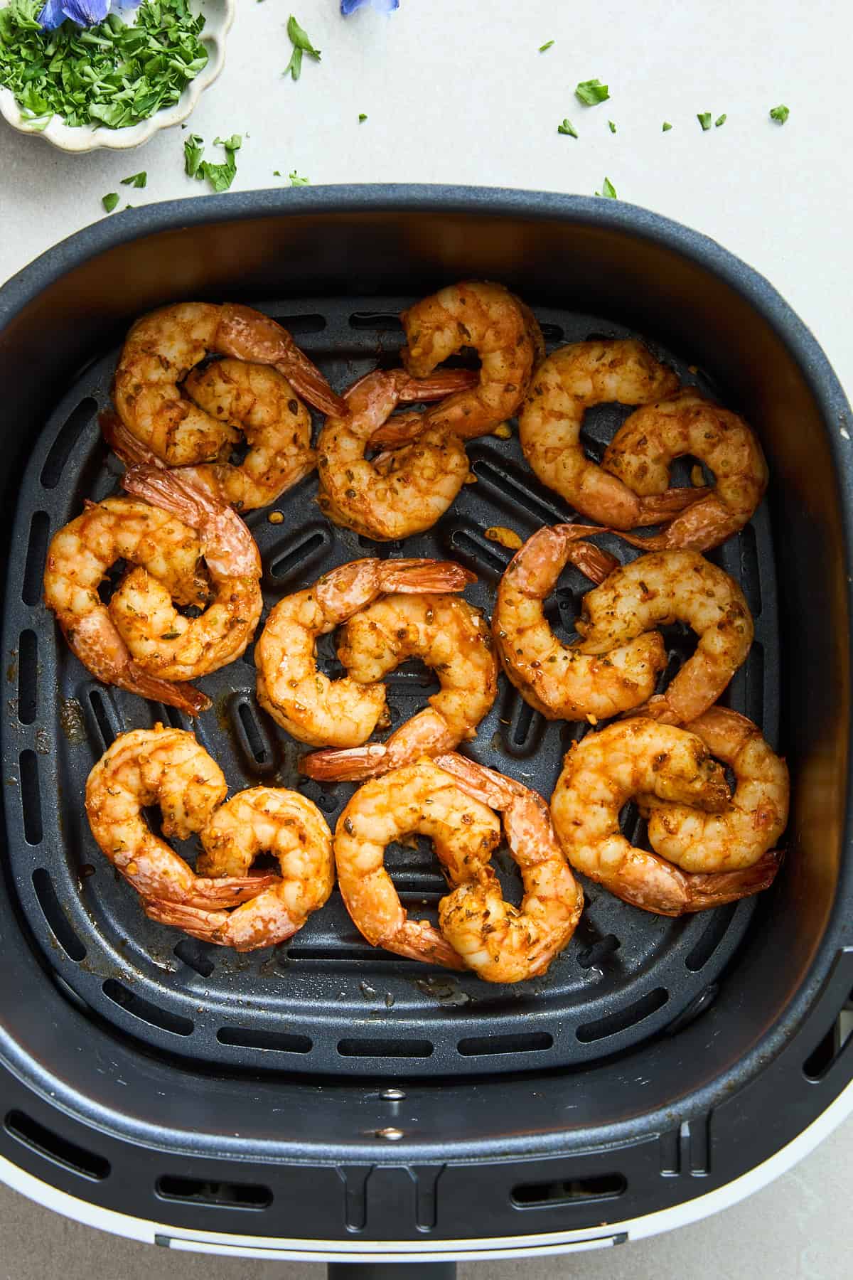 Cooked air fryer shrimp in an air fryer basket.