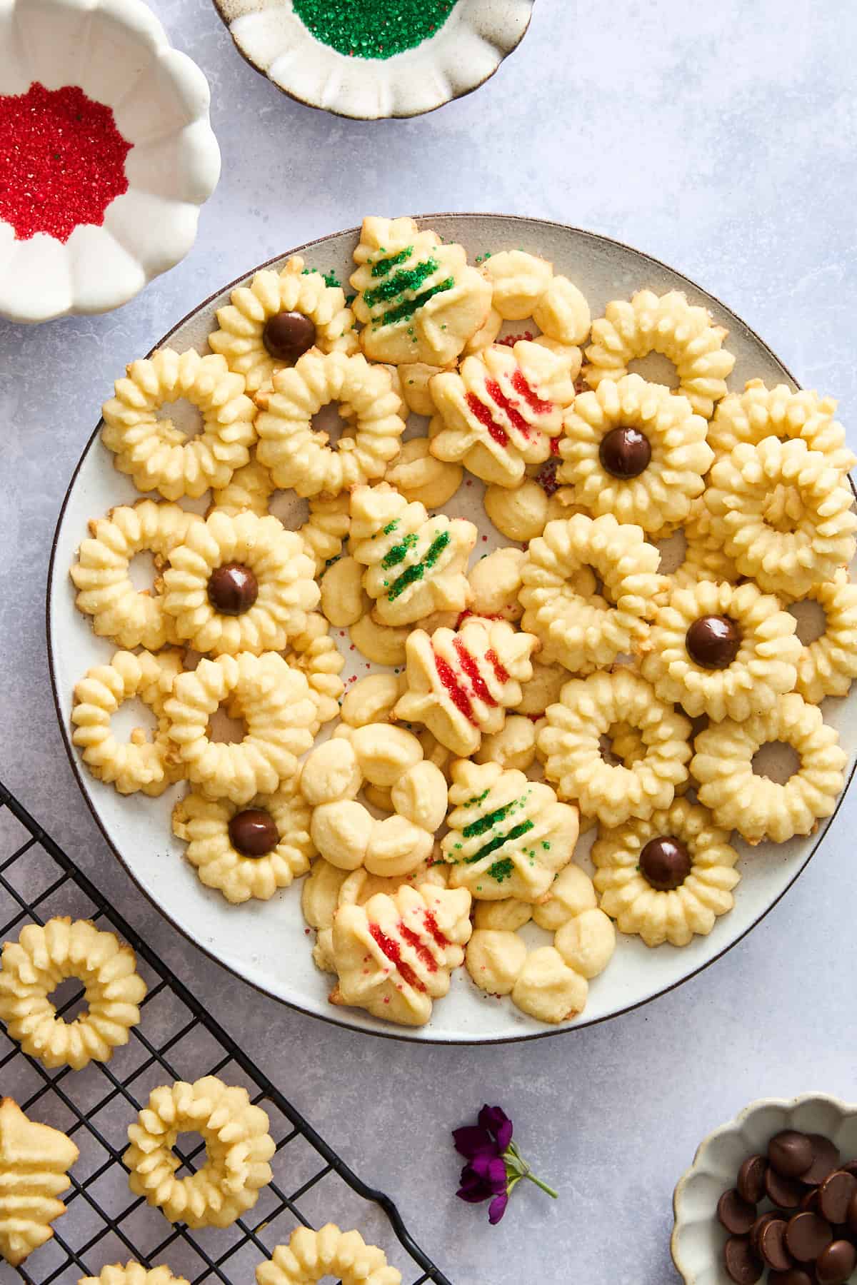 A platter of spritz cookies, some topped with a chocolate chip and some with sprinkles. 