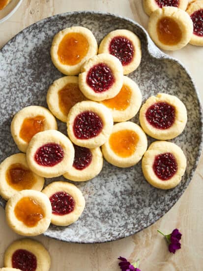 A plate of jam thumbprint cookies with apricot and raspberry jam.