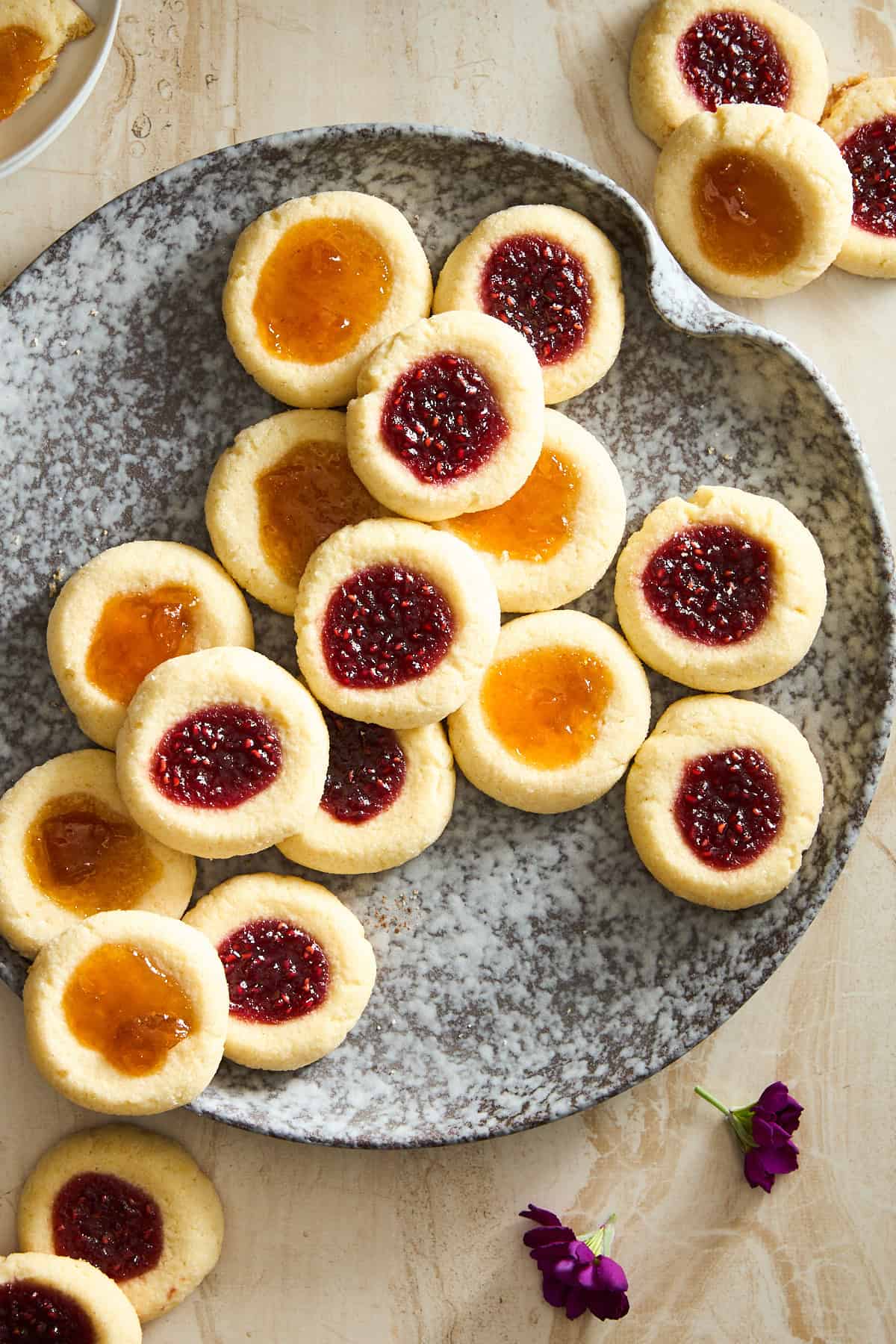 A plate of jam thumbprint cookies with raspberry and apricot jam. 