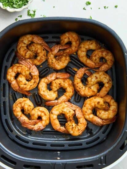 Cooked air fryer shrimp in an air fryer basket.