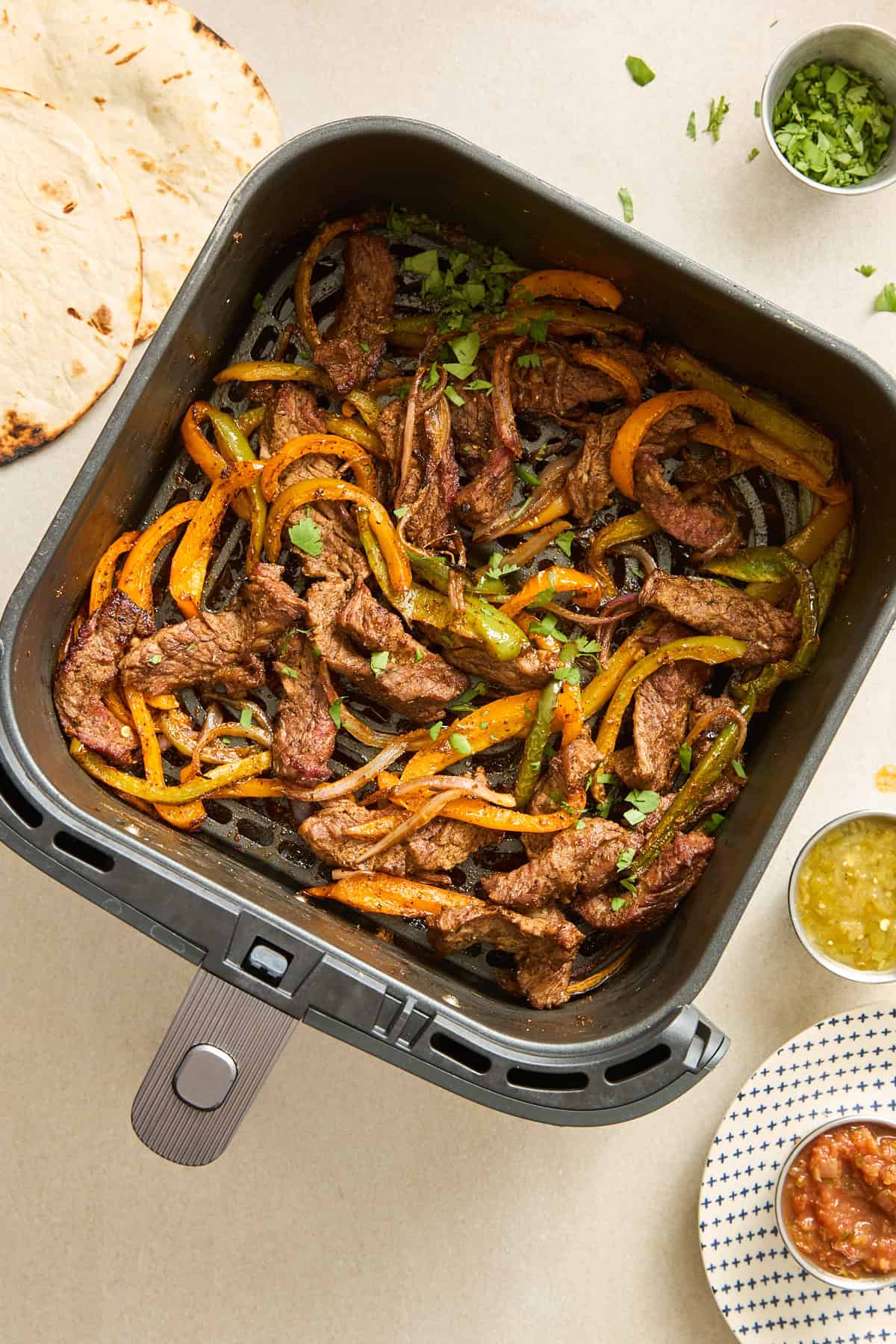 An air fryer basket full of steak fajitas. 