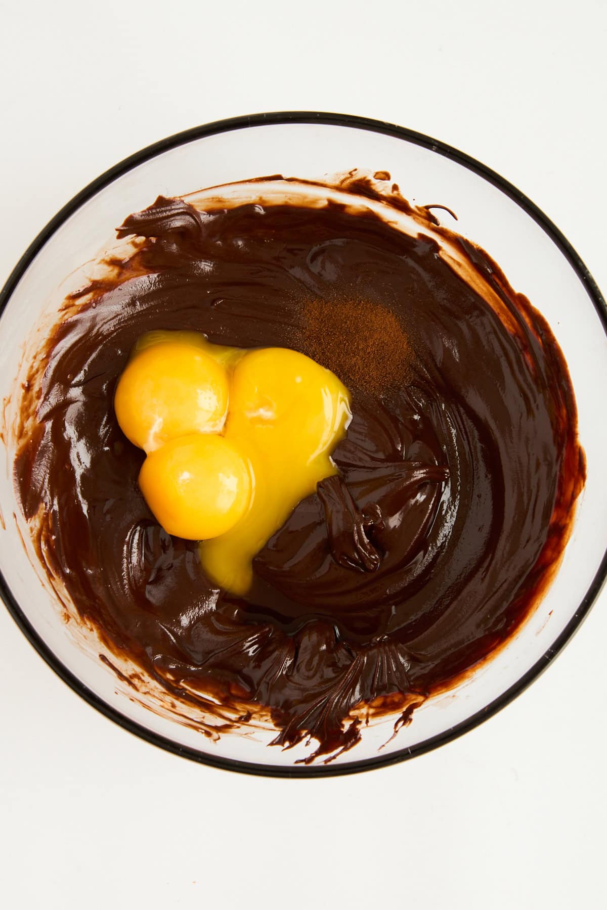 Egg yolks in a bowl with melted chocolate. 