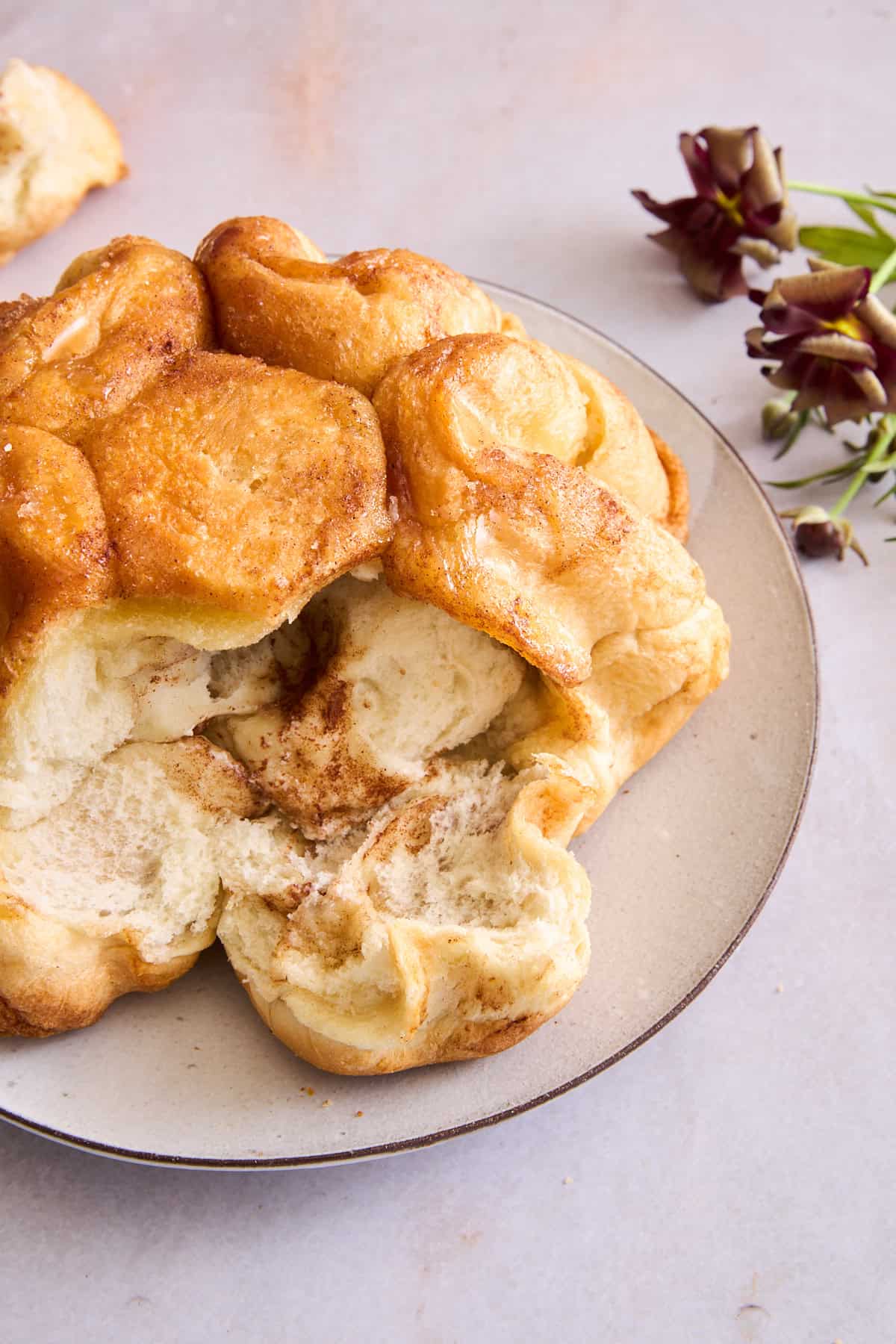 Cinnamon sugar pull apart bread on a plate with pieces pulled off. 