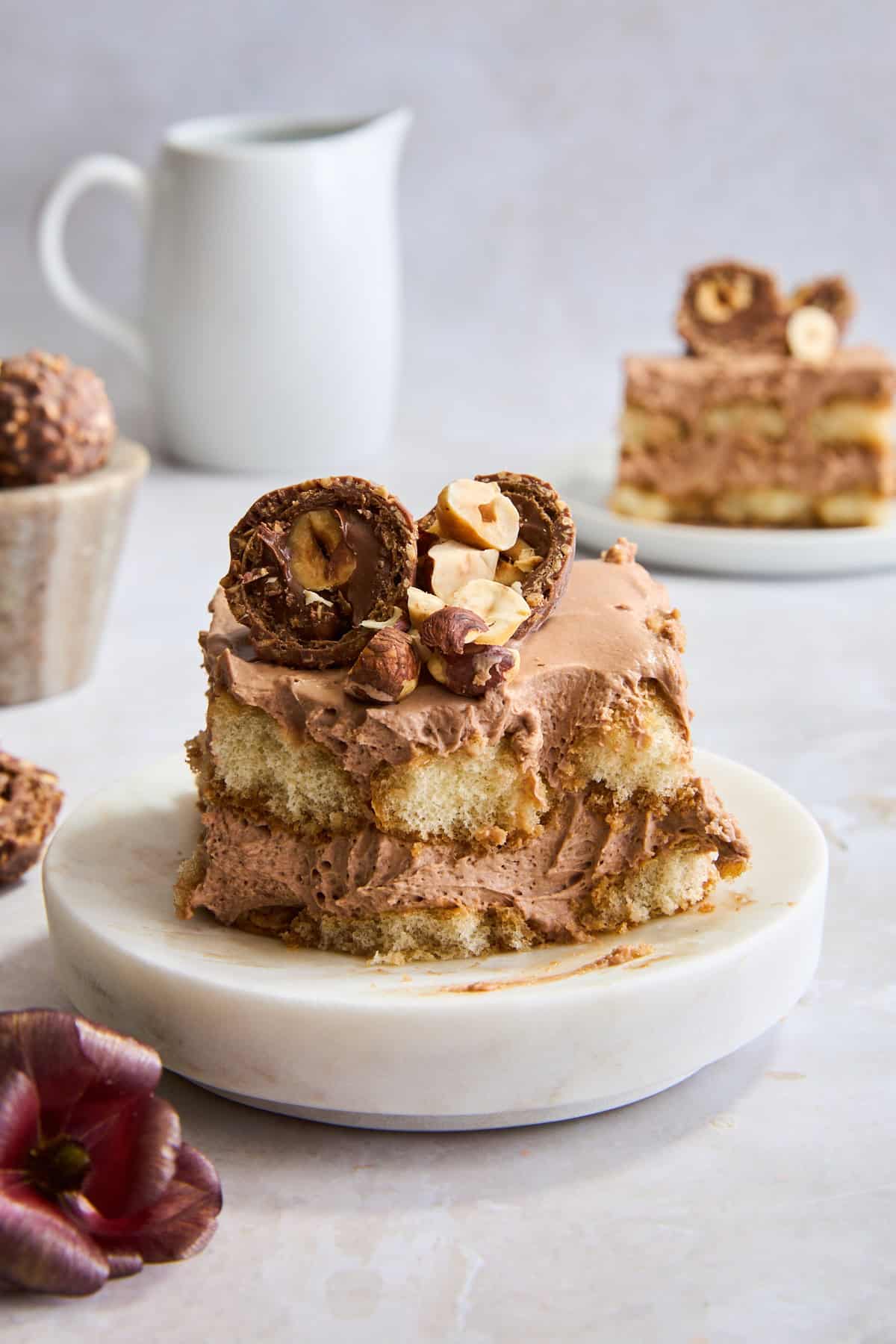 A slice of no-bake Nutella tiramisu on a plate topped with a ferro rocher candy. 