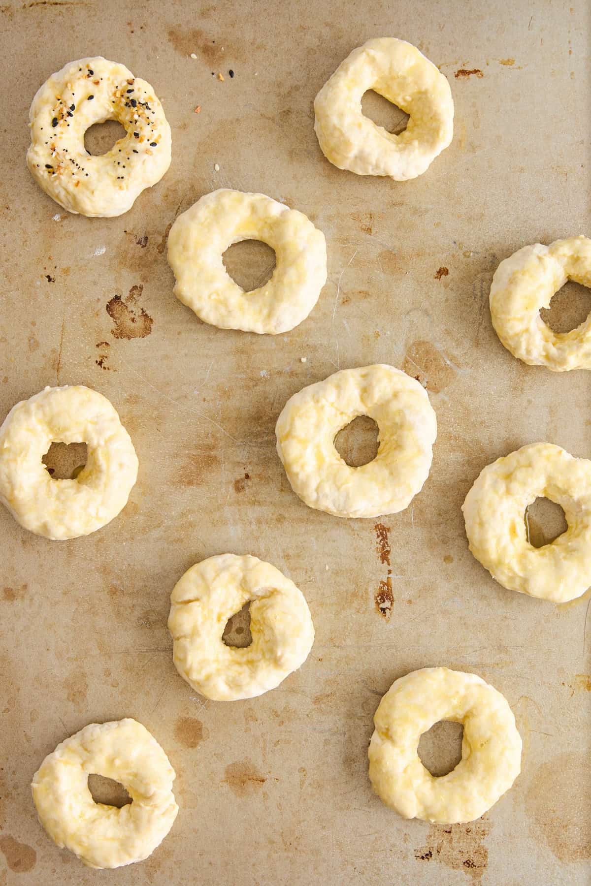 Unbaked cottage cheese bagels on a sheet pan. 